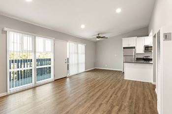 an empty living room with a balcony and a kitchen